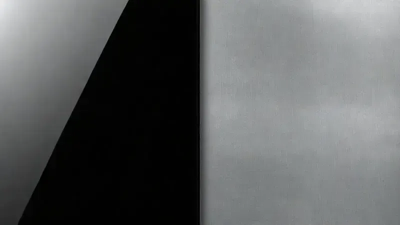 Texturas lado a lado de vidro preto elegante e aço inoxidável escovado durável, representando materiais de fogão.