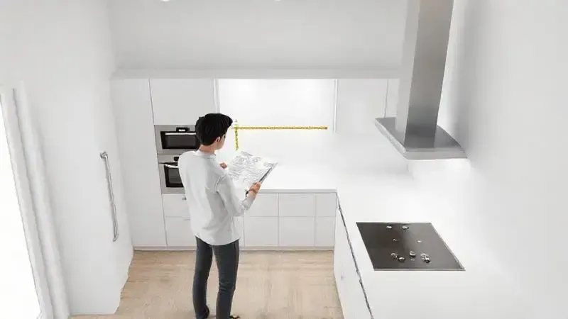Pessoa em uma cozinha planejando o espaço e medindo a bancada para a instalação de um novo eletrodoméstico.